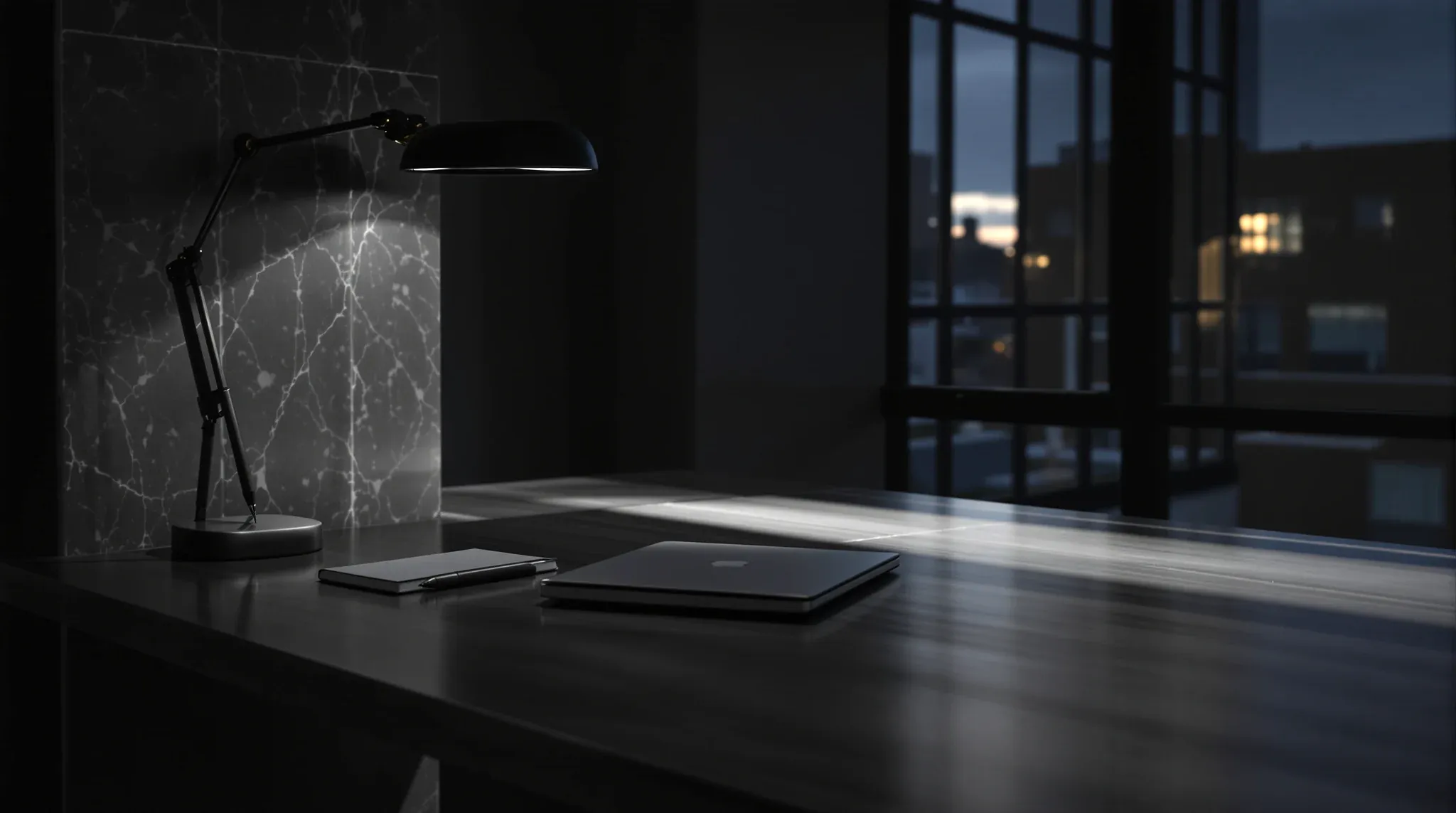 A minimal modern desk, a closed laptop and a notebook under one shaft of light