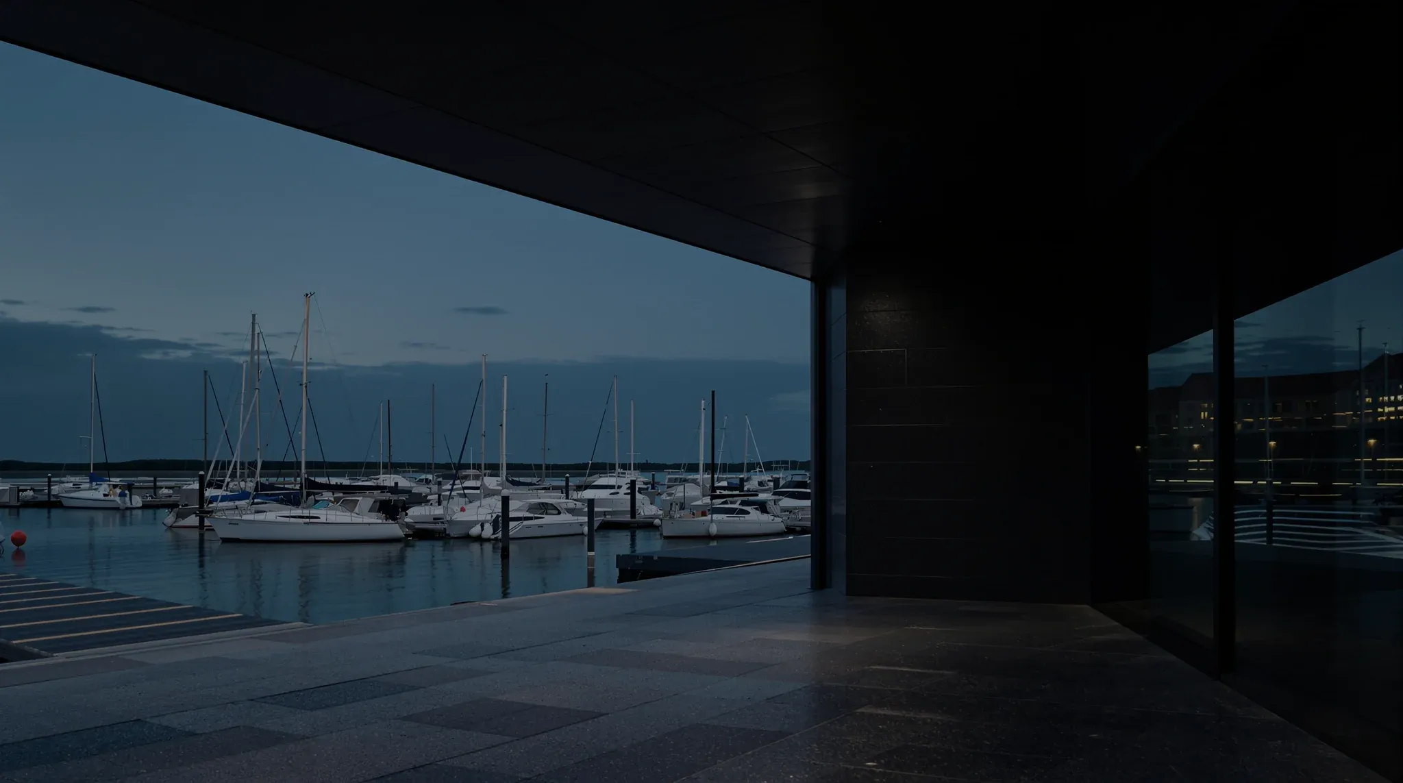 A modern marina on the Solent at dusk, yachts moored along pontoons on flat still water