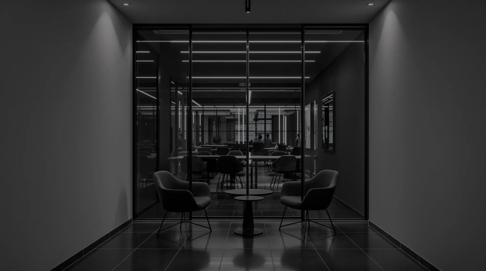 A small modern interview room, two chairs either side of a dark table behind a glass wall